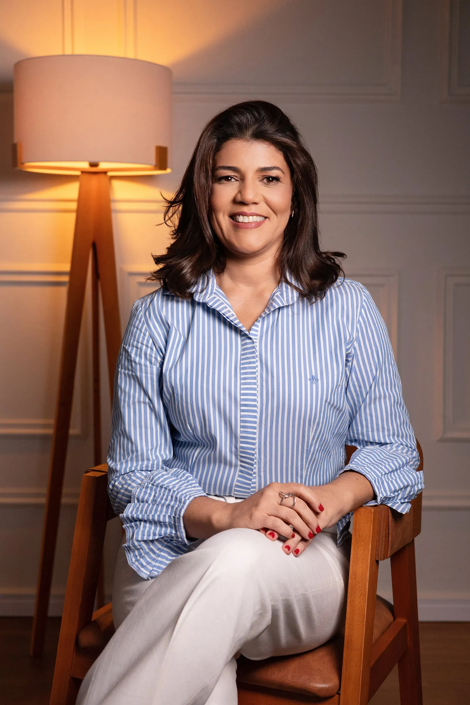Dra. Lilian Figueiredo sentada em uma cadeira de madeira, sorrindo