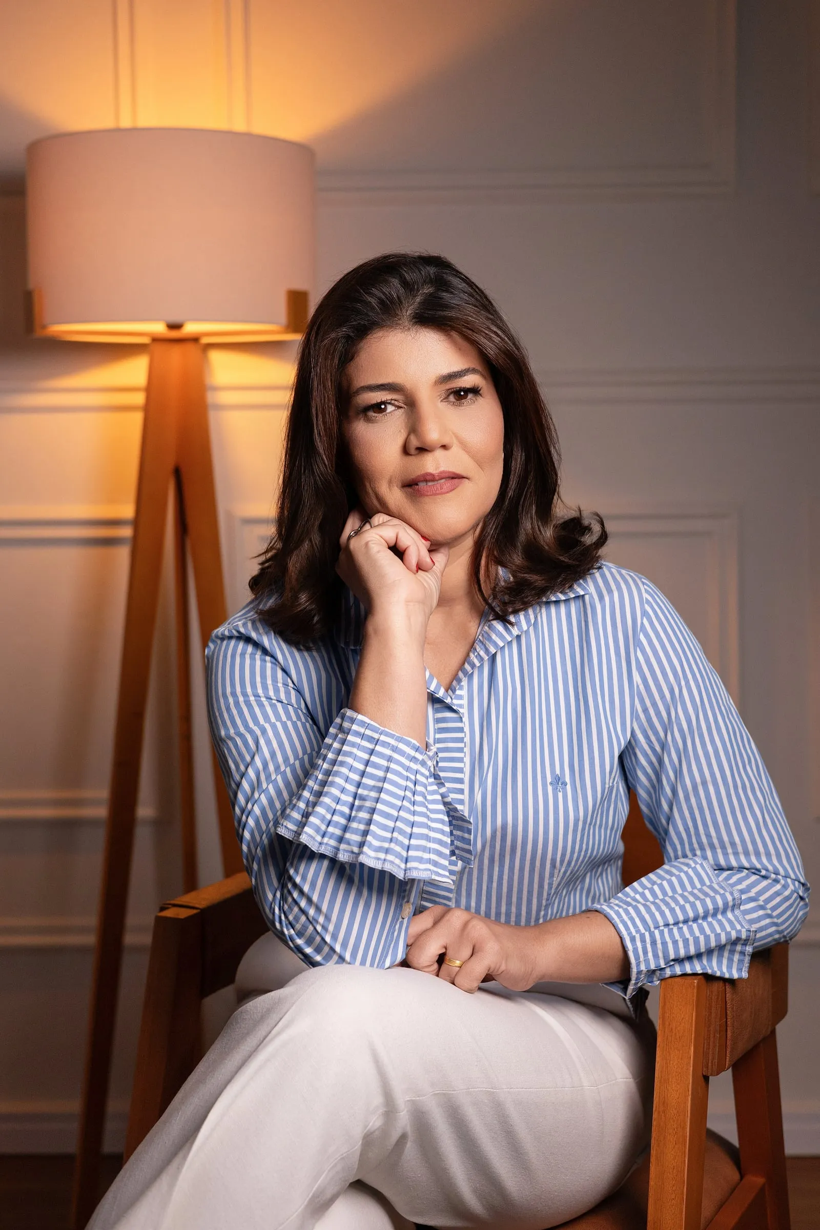 Dra. Lilian Figueiredo com a mão no queixo, ao lado de uma luminária